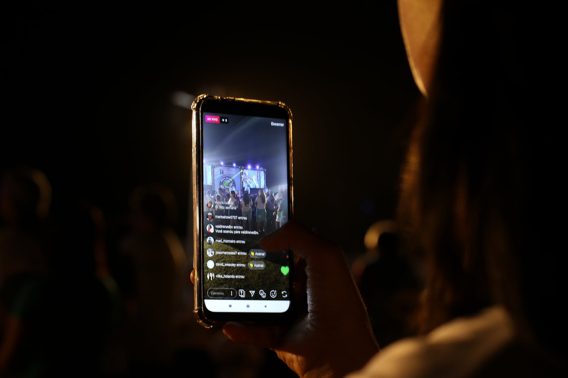 close up photo of a person recording a live performance with her cell phone